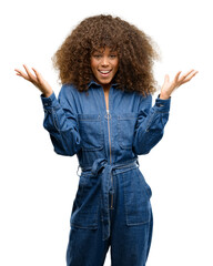 Poster - African american woman wearing blue jumpsuit happy and surprised cheering expressing wow gesture