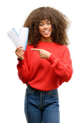 Wall Mural - African american woman holding airline boarding pass tickets very happy pointing with hand and finger