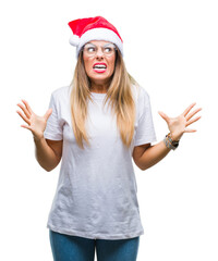 Sticker - Young beautiful woman wearing christmas hat over isolated background crazy and mad shouting and yelling with aggressive expression and arms raised. Frustration concept.