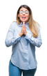 Young beautiful business woman wearing glasses over isolated background begging and praying with hands together with hope expression on face very emotional and worried. Asking for forgiveness.