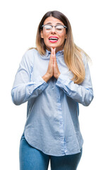 Wall Mural - Young beautiful business woman wearing glasses over isolated background begging and praying with hands together with hope expression on face very emotional and worried. Asking for forgiveness.