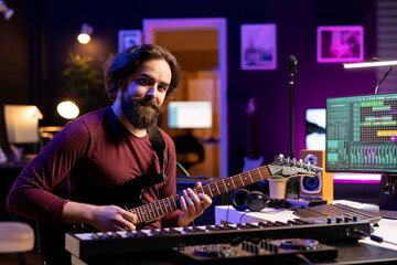 Fototapete - Portrait of confident artist playing acoustic guitar in his home studio, prepares for a new audio recording session to edit tracks for music industry. Songwriter guitarist composing songs.