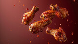 Fototapeta Desenie - Barbecue chicken wings in mid-air with droplets of sauce and a sprinkle of spices. Dark red background. Concept for International Chicken Wing Day.