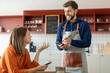 © Home-stock - Handsome smiling waiter using application on digital tablet, taking order of young female client in pastry shop of cafe