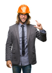 Poster - Young handsome architec man with long hair wearing safety helmet over isolated background smiling and confident gesturing with hand doing size sign with fingers while looking and the camera