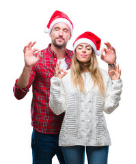 Wall Mural - Young couple in love wearing christmas hat over isolated background relax and smiling with eyes closed doing meditation gesture with fingers. Yoga concept.