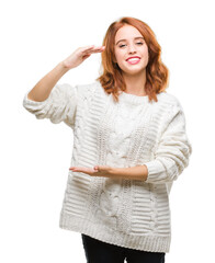 Poster - Young beautiful woman over isolated background wearing winter sweater gesturing with hands showing big and large size sign, measure symbol. Smiling looking at the camera. Measuring concept.