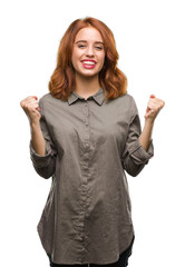 Canvas Print - Young beautiful woman over isolated background celebrating surprised and amazed for success with arms raised and open eyes. Winner concept.