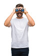 © Krakenimages.com - Young handsome man looking through binoculars over isolated background with a happy face standing and smiling with a confident smile showing teeth