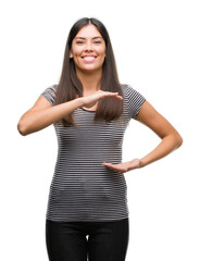 Sticker - Young beautiful hispanic woman gesturing with hands showing big and large size sign, measure symbol. Smiling looking at the camera. Measuring concept.