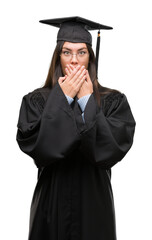 Poster - Young hispanic woman wearing graduated cap and uniform shocked covering mouth with hands for mistake. Secret concept.