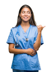 Wall Mural - Young arab doctor surgeon woman over isolated background smiling with happy face looking and pointing to the side with thumb up.