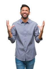 Wall Mural - Adult hispanic man over isolated background crazy and mad shouting and yelling with aggressive expression and arms raised. Frustration concept.