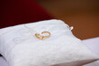 elegant gold wedding bands on satin pillow with red backdrop