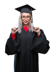 Wall Mural - Young blonde woman wearing graduate uniform over isolated background looking confident with smile on face, pointing oneself with fingers proud and happy.