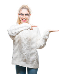 Poster - Young beautiful blonde woman wearing glasses over isolated background amazed and smiling to the camera while presenting with hand and pointing with finger.