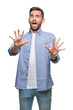 © Krakenimages.com - Young handsome man wearing white t-shirt over isolated background afraid and terrified with fear expression stop gesture with hands, shouting in shock. Panic concept.
