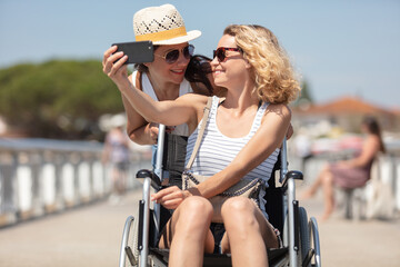 woman takes care her friend on wheelchair