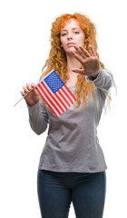 Poster - Young redhead woman holding flag of United States of America with open hand doing stop sign with serious and confident expression, defense gesture