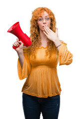 Wall Mural - Young redhead woman holding megaphone cover mouth with hand shocked with shame for mistake, expression of fear, scared in silence, secret concept