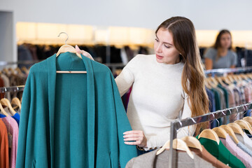 Wall Mural - Smiling woman shows a stylish jacket in the women clothing store