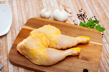 Wall Mural - Home cooking. Fresh raw chicken legs and condiments prepared for roasting on wooden table