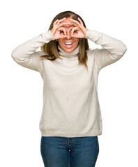 Sticker - Beautiful middle age adult woman wearing winter sweater over isolated background doing ok gesture like binoculars sticking tongue out, eyes looking through fingers. Crazy expression.