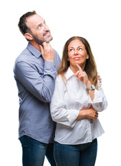 Wall Mural - Middle age hispanic business couple over isolated background with hand on chin thinking about question, pensive expression. Smiling with thoughtful face. Doubt concept.