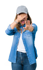 Wall Mural - Beautiful middle age woman wearing sport cap over isolated background covering eyes with hands and doing stop gesture with sad and fear expression. Embarrassed and negative concept.