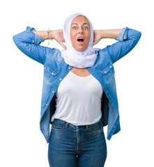 Poster - Middle age eastern arab woman wearing arabian hijab over isolated background Crazy and scared with hands on head, afraid and surprised of shock with open mouth