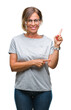 Middle age senior hispanic woman wearing glasses over isolated background with a big smile on face, pointing with hand and finger to the side looking at the camera.