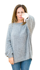 Wall Mural - Beautiful middle age woman wearing winter sweater over isolated background looking unhappy and angry showing rejection and negative with thumbs down gesture. Bad expression.