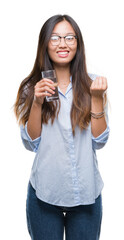 Sticker - Young asian woman drinking a glass of water over isolated background screaming proud and celebrating victory and success very excited, cheering emotion