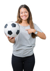 Canvas Print - Young beautiful brunette woman holding soccer football ball over isolated background with surprise face pointing finger to himself