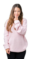 Canvas Print - Young beautiful brunette woman wearing pink winter sweater over isolated background looking confident at the camera with smile with crossed arms and hand raised on chin. Thinking positive.