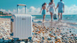 Suitcase in pebbled beach with blurred family in the background. Summer vacations with family concept