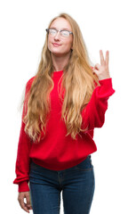 Poster - Blonde teenager woman wearing red sweater showing and pointing up with fingers number two while smiling confident and happy.