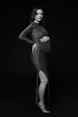 Wall Mural - Black and white portrait of pregnant female in sequin dress with hands near pregnant belly.