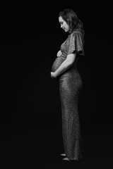 Wall Mural - Black and white portrait of pregnant female in sequin dress with hands near pregnant belly.