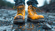 Close-up of rugged yellow boots on a rocky terrain with splattered mud.