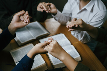 Wall Mural - Christian Family prayer and worship. Christian group of people holding hands and praying worships to believe and Bible on a wooden table prayer meeting concept. Church Community pray together