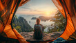 Person sitting in tent admiring the breathtaking sunrise view over a mountainous landscape.