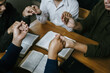 Christian Family prayer and worship. Christian group of people holding hands and praying worships to believe and Bible on a wooden table prayer meeting concept. Church Community pray together