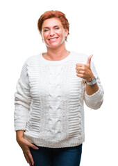 Poster - Atrractive senior caucasian redhead woman wearing winter sweater over isolated background doing happy thumbs up gesture with hand. Approving expression looking at the camera with showing success.