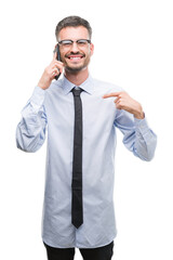 Sticker - Young business adult man talking on the phone with surprise face pointing finger to himself