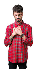 Wall Mural - Young handsome man wearing glasses over isolated background smiling with hands on chest with closed eyes and grateful gesture on face. Health concept.