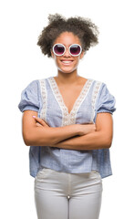 Canvas Print - Young afro american woman wearing glasses over isolated background happy face smiling with crossed arms looking at the camera. Positive person.