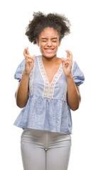Wall Mural - Young afro american woman over isolated background smiling crossing fingers with hope and eyes closed. Luck and superstitious concept.
