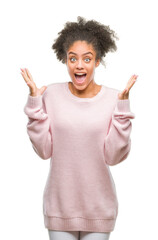 Canvas Print - Young afro american woman wearing winter sweater over isolated background celebrating crazy and amazed for success with arms raised and open eyes screaming excited. Winner concept