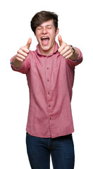 Wall Mural - Young handsome business man over isolated background approving doing positive gesture with hand, thumbs up smiling and happy for success. Looking at the camera, winner gesture.